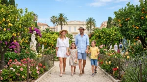 Famille joyeuse se promenant dans les jardins Biovès de Menton parmi les fleurs et agrumes ensoleillés.