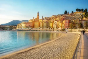 Vue panoramique de Menton depuis la plage des Sablettes, vieille ville colorée et mer Méditerranée au coucher du soleil